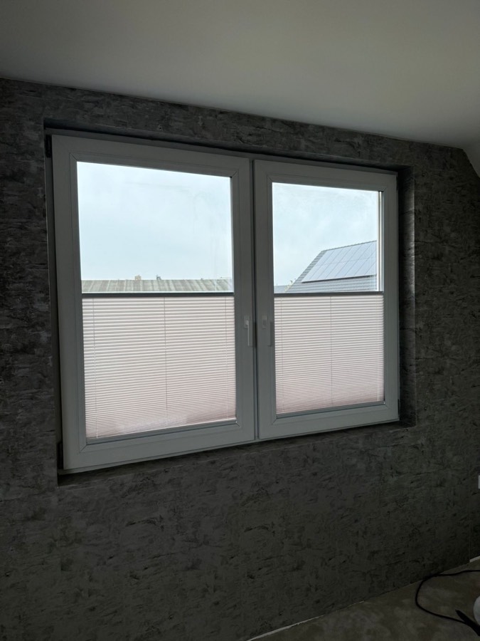 Plissé gordijnen op twee draai-kiepramen in een kamer met donkere wand